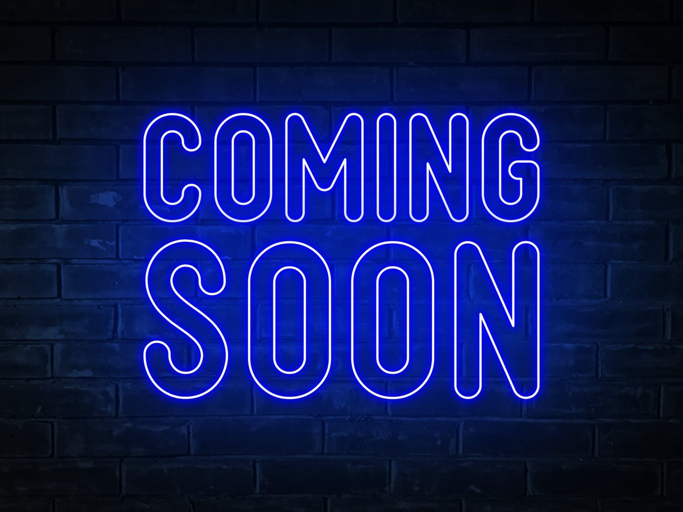 Coming soon - blue neon light word on brick wall background