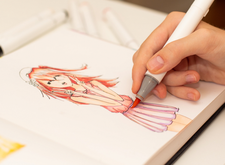 Girl's hand drawing anime manga sketch with alcohol based sketch markers.